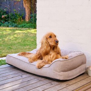 A cocker spaniel laying on a SnugSide crate bed on a deck